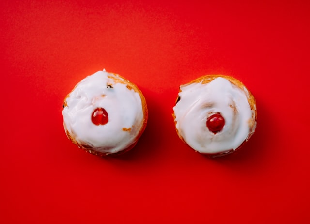 2 iced buns with cherries that look like breasts on red