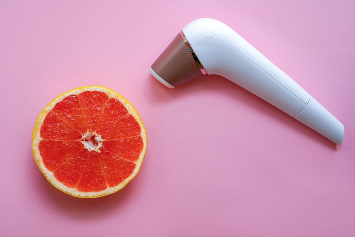  Vibrator next to a slice of pink grapefruit on a pink background