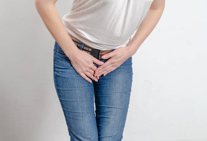 Woman holding her crotch because of vulva pain