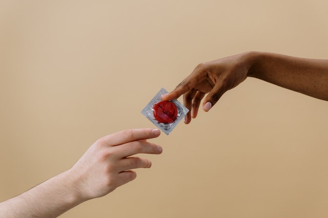 Hand passing condom to another hand
