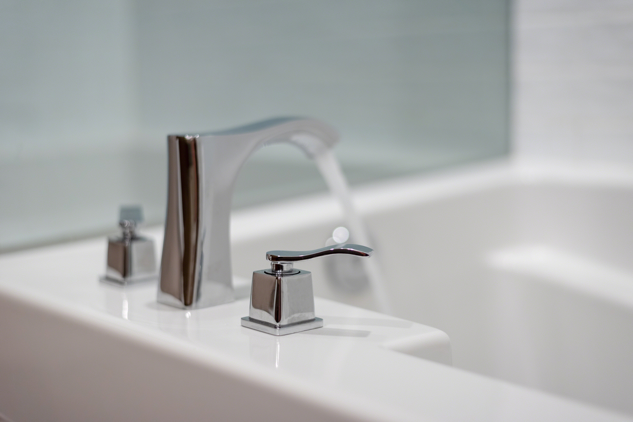 Closeup of chrome faucet on white bath tub