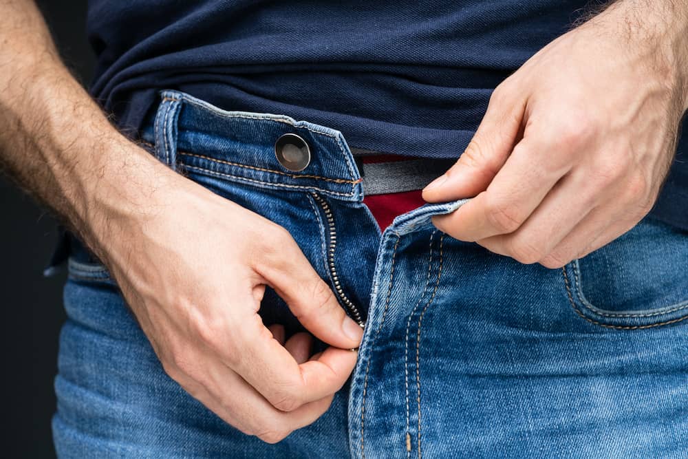 Man unzipping jeans showing signs of male sexual arousal