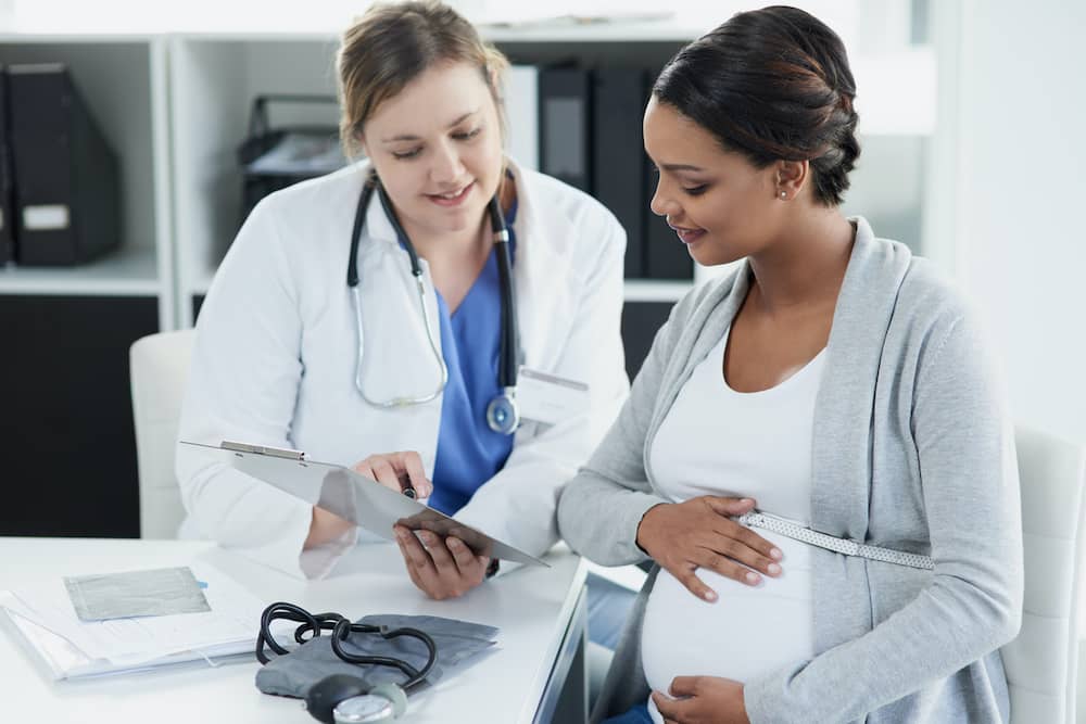 Pregnant woman and doctor looking at CVS chorionic villus sampling test results