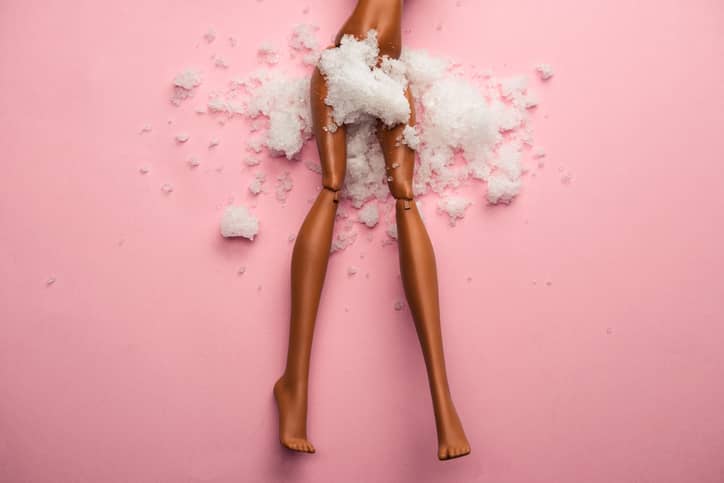 塑料娃娃腿被粉红色的雪覆盖