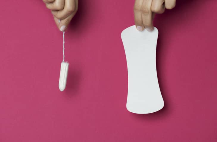 Person holding a tampon and a sanitary towel