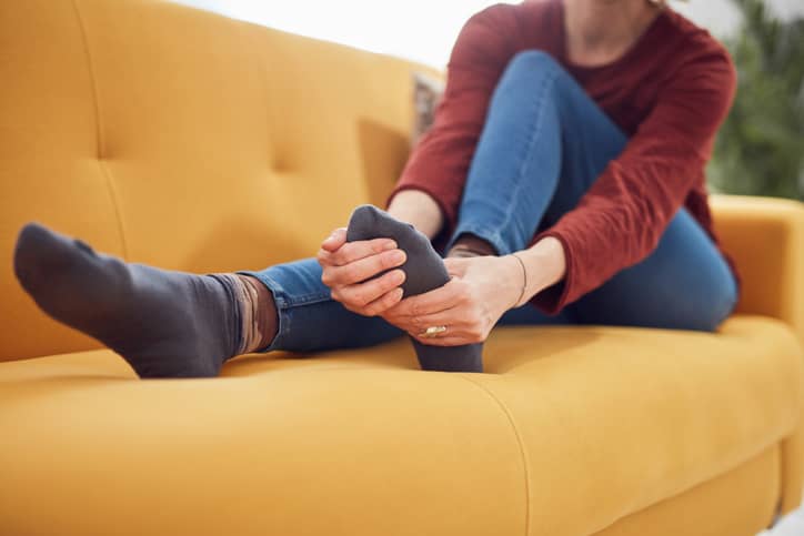 Person sitting on couch holding foot