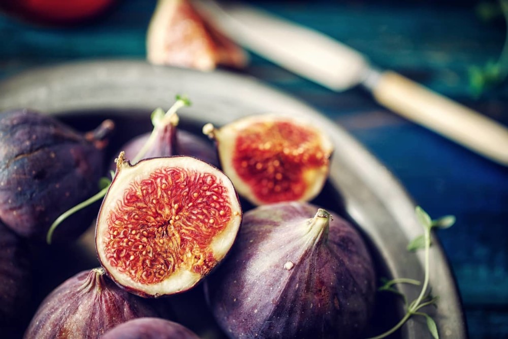 Figs in a bowl with 1 cut open to show fig benefits