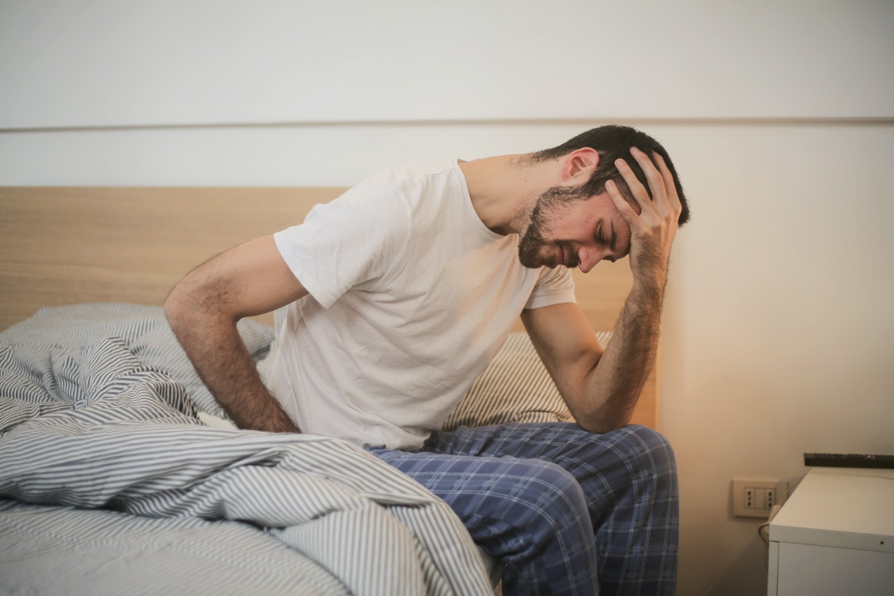 男人坐在床上醒来时头痛（信用 - 安德里亚·皮亚卡迪奥）