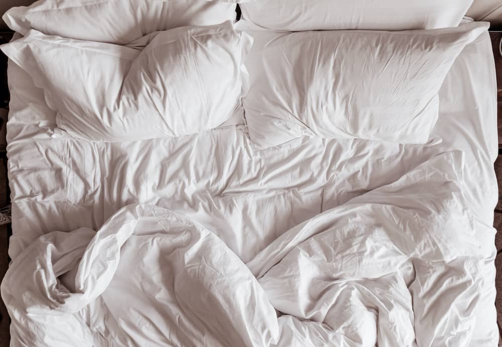 White bedsheets and pillow cases on unmade bed
