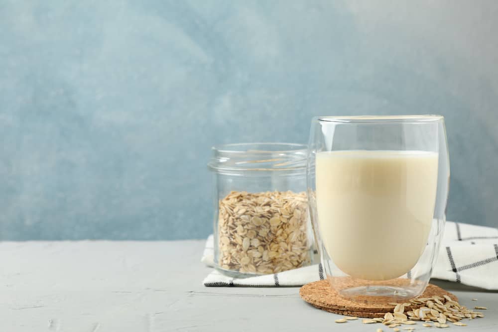 Glass of oat milk and jar of oats 
