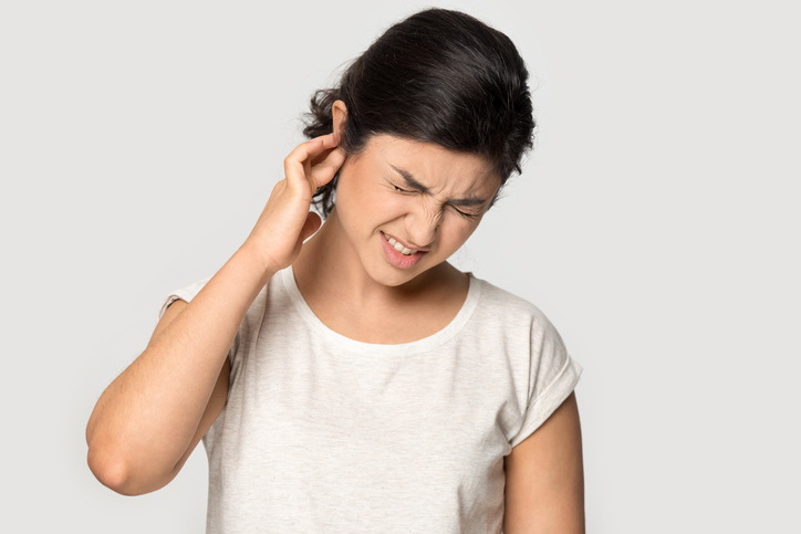 Woman with earache holding onto ear