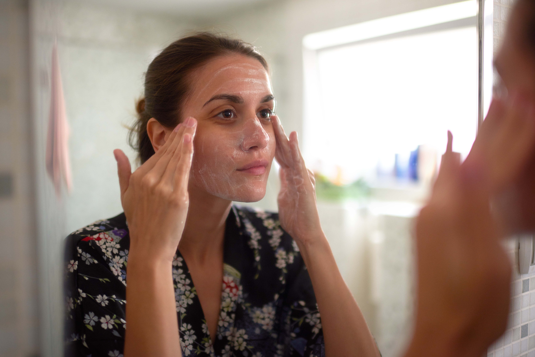 Woman with acne cleaning her face