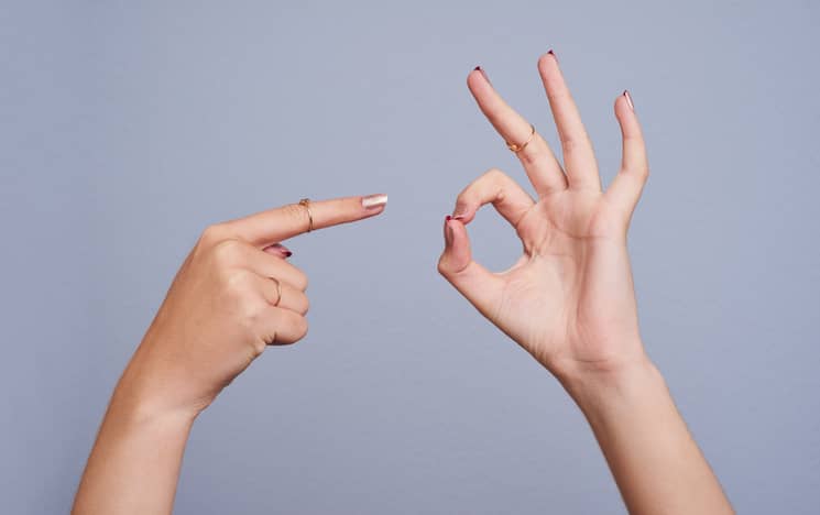 Person pointing with one hand and making a circle with the other to represent penetrative sex