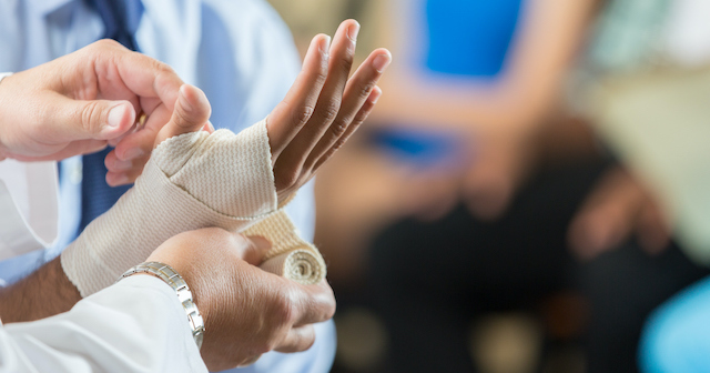 Hand with sprained wrist being wrapped in a bandage by doctor