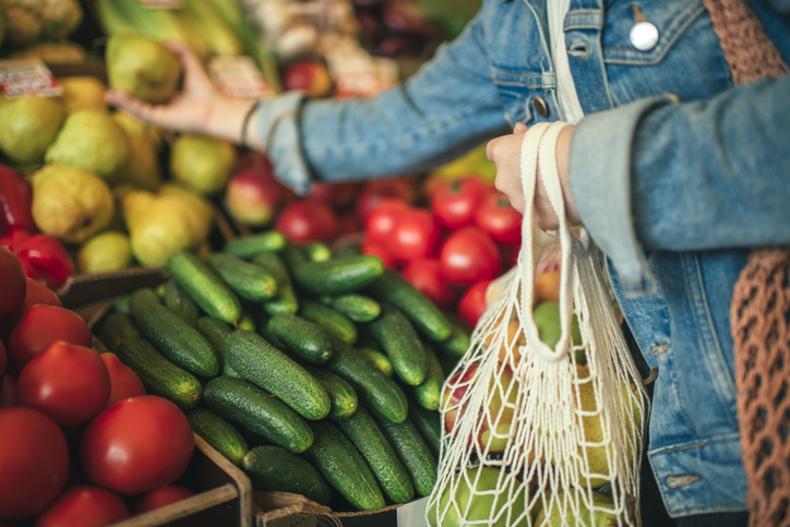 Woman buying individual vegetables and using a reusable bag
