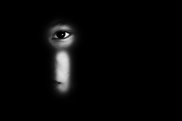 Eye of a boy looking through a keyhole, child abuse concept