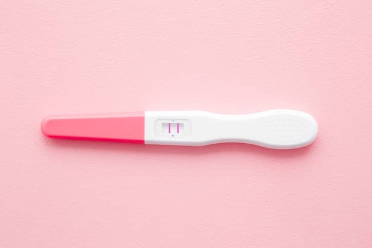 Positive pregnancy test on a pink background 