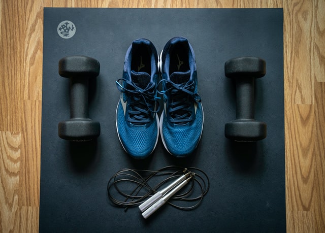 Trainers, a skipping rope and dumbbell weights on a workout mat