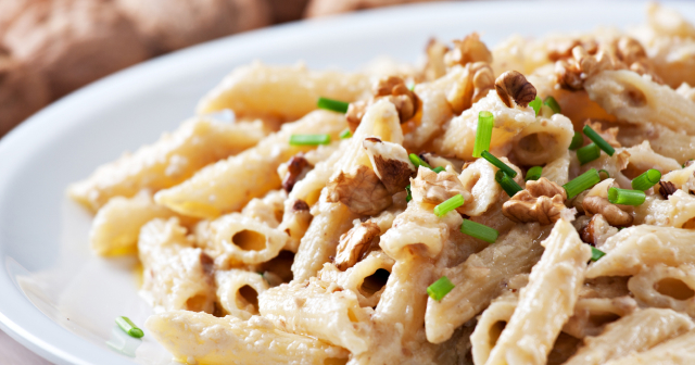 Walnut pasta on a plate with chopped herbs is way to increase walnuts in your diet for better sleep