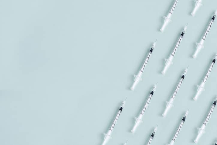 Rows of typhoid vaccine syringes on a light blue background