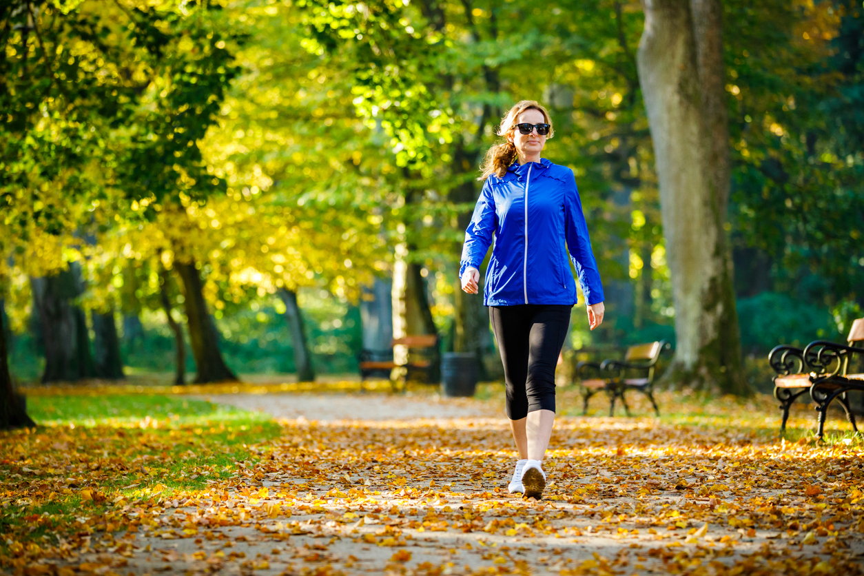 Middle-aged woman wearing sunglasses out walking in a park 