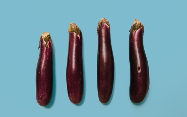 4 aubergines in a row against blue background