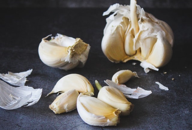 A broken up garlic bulb on a dark countertop