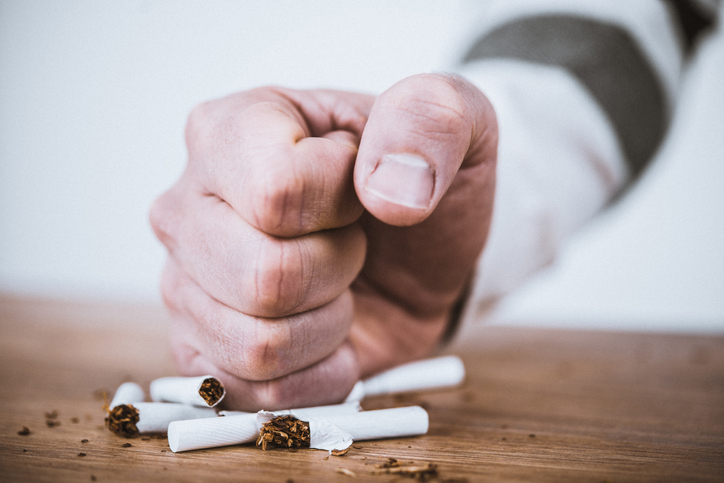 Close up of a man's hand smashing cigarettes on a table