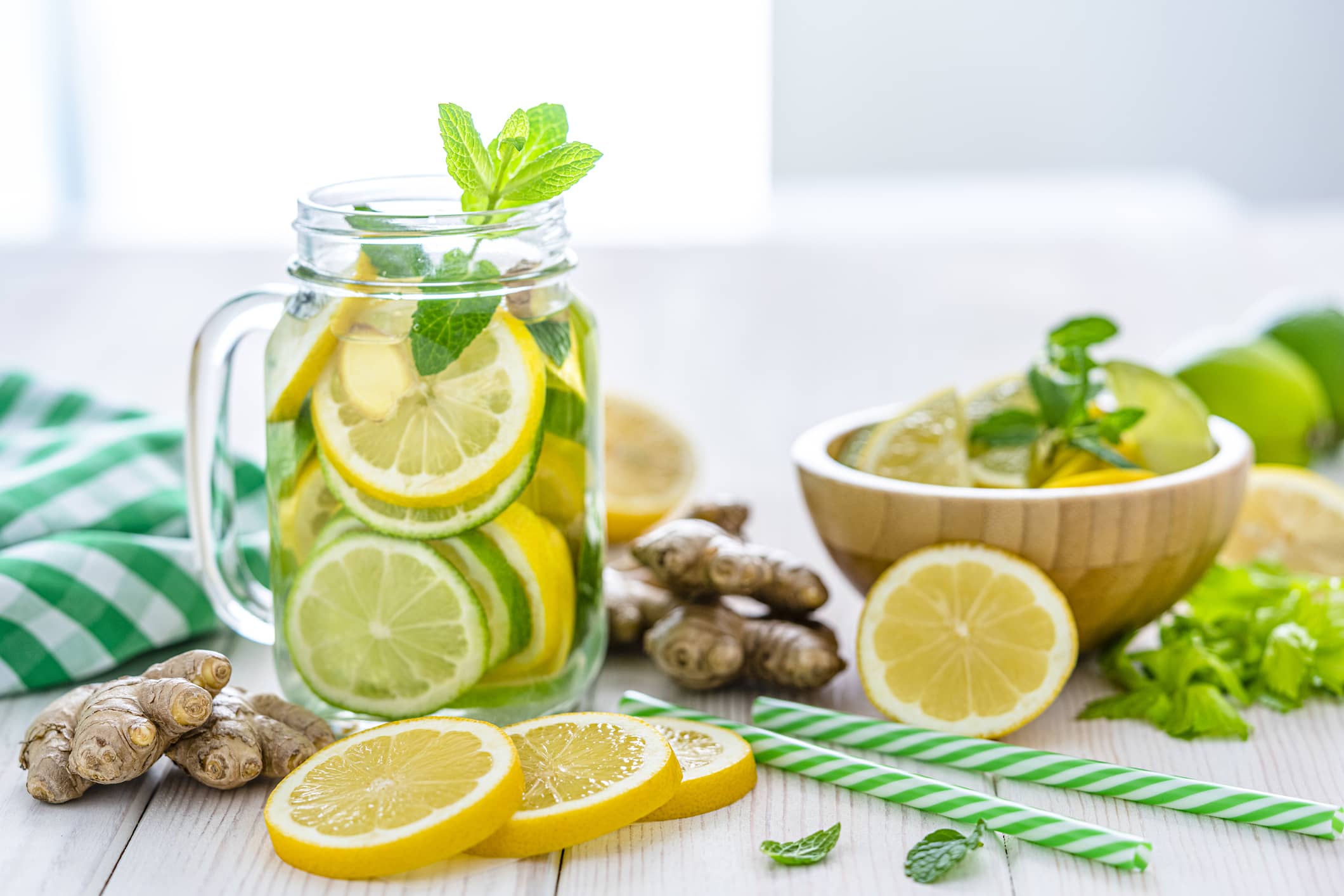 Glass of water with pieces of fresh lemon, lime, mint and ginger