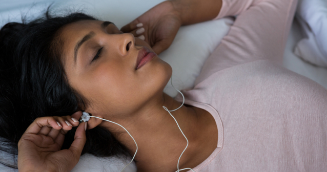 女人躺在床上睡觉，戴着耳机听音乐