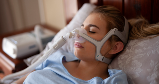 Woman sleeping using a CPAP machine to help treat sleep apnoea