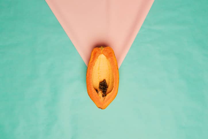 Studio shot of a papaya slice against turquoise a background