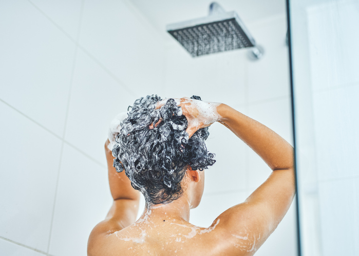 Woman washing her hair with shampoo in the shower at home