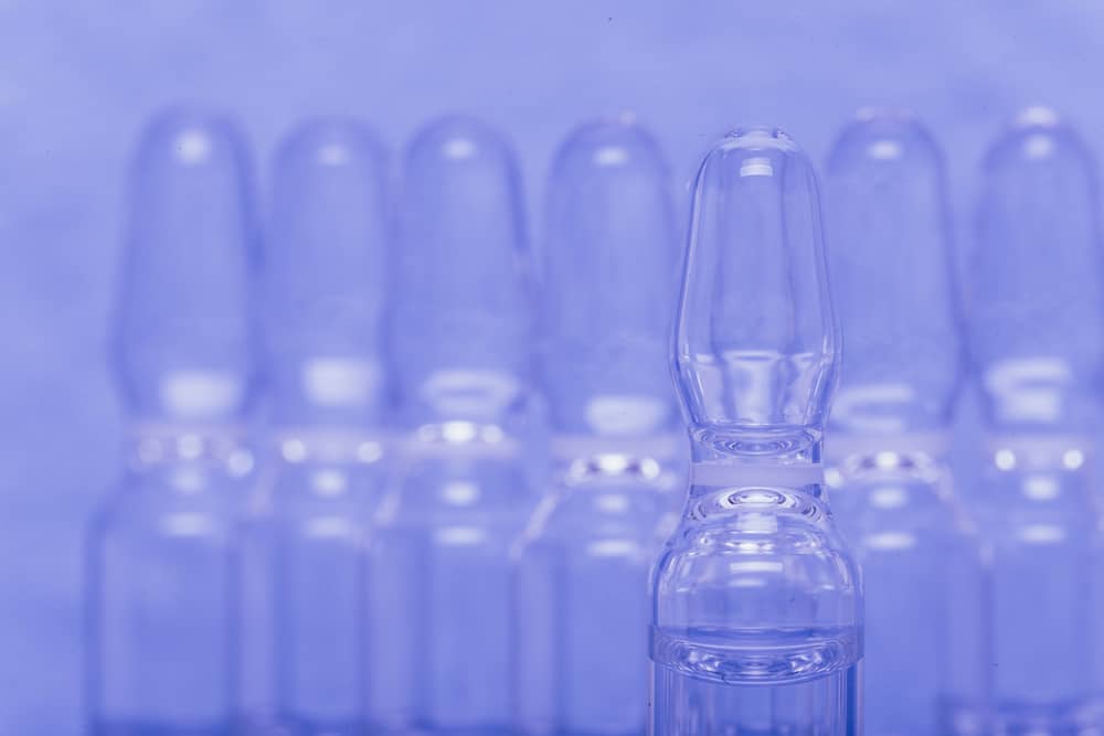 Glass medical bottles for medicine on purple background