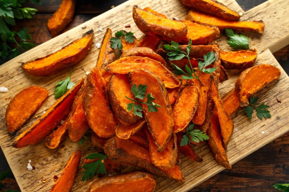 Roast sweet potato wedges with parsley on chopping board