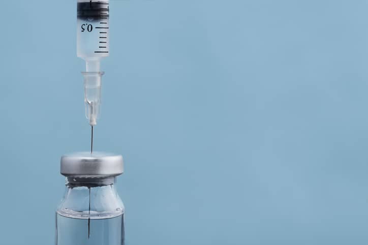 Vial of typhoid vaccine with syringe needle in the top
