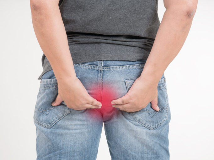 Back of a man wearing jeans with a red focus on the anus, anal problems concept