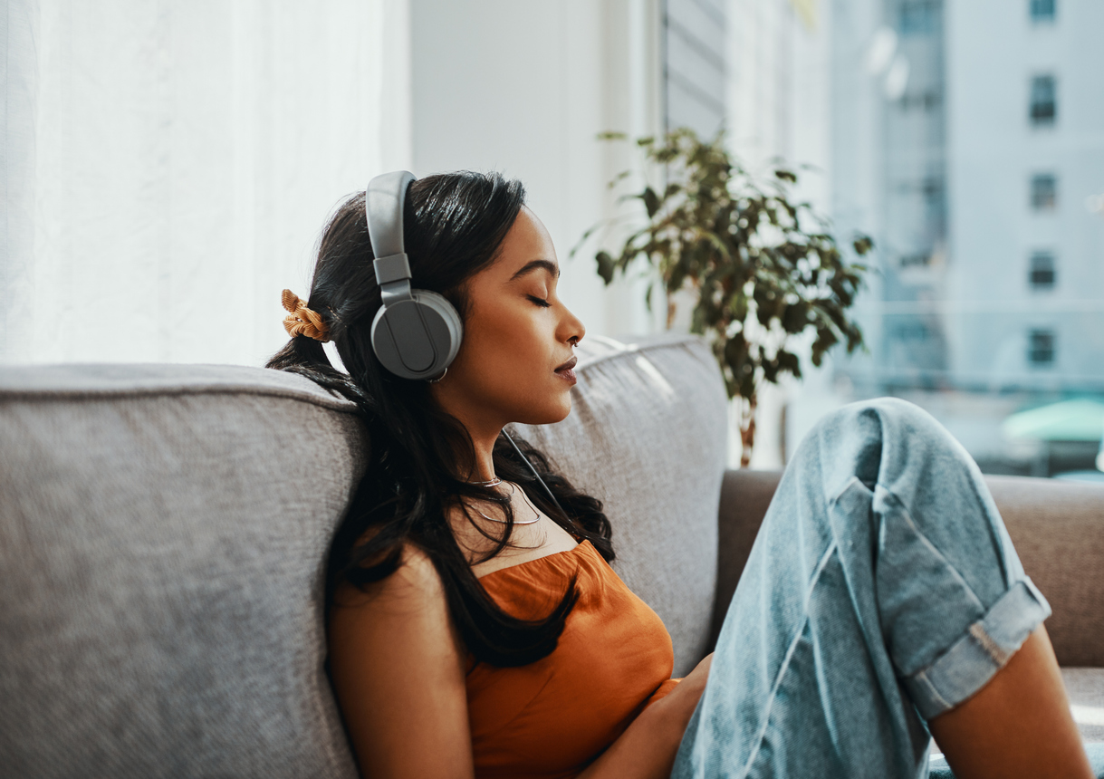 女人在家里放松沙发时使用耳机