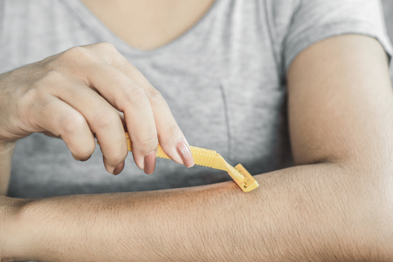 Woman shaving her arm