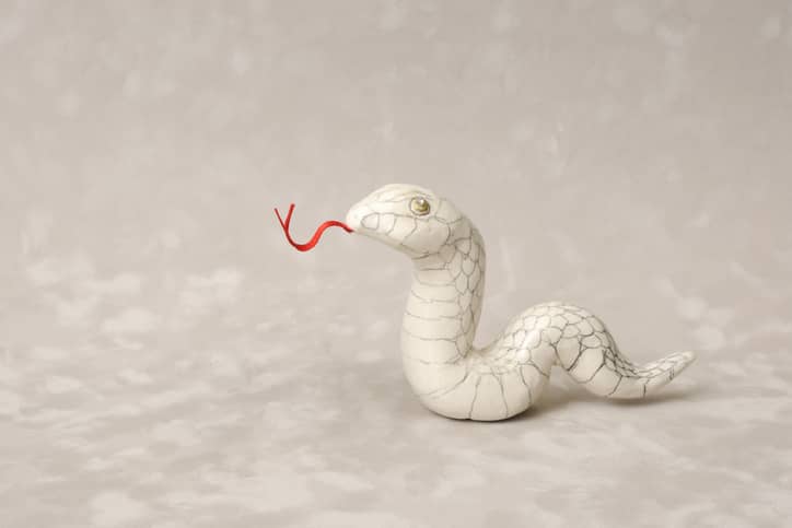 White ceramic snake with red tongue on a cream background