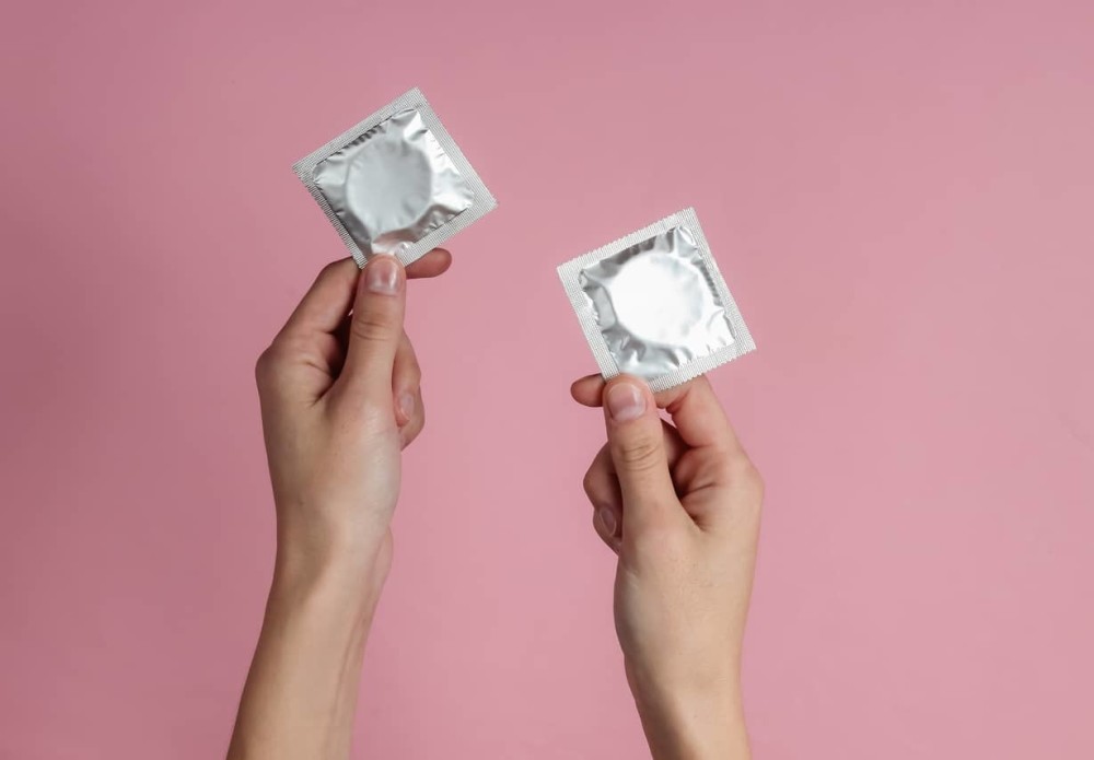 2 hands holding up condoms to ask can you have sex on your period and get pregnant