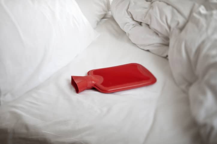 Red hot water bottle on an unmade bed
