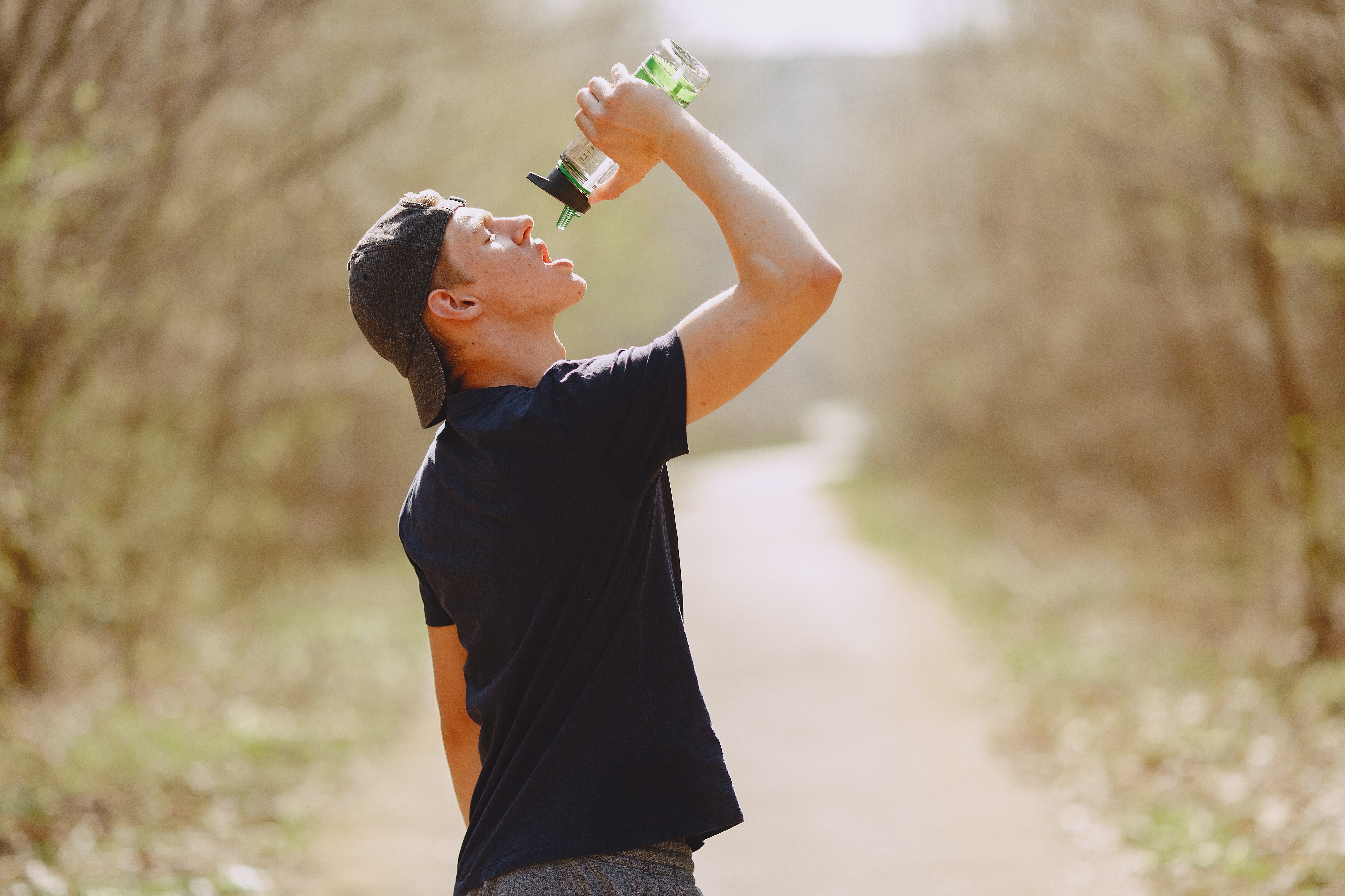 Man outside doing exercise drinking from water bottle