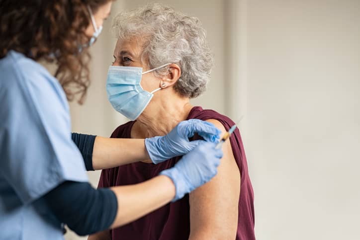 Older person getting a COVID-19 vaccine from a nurse