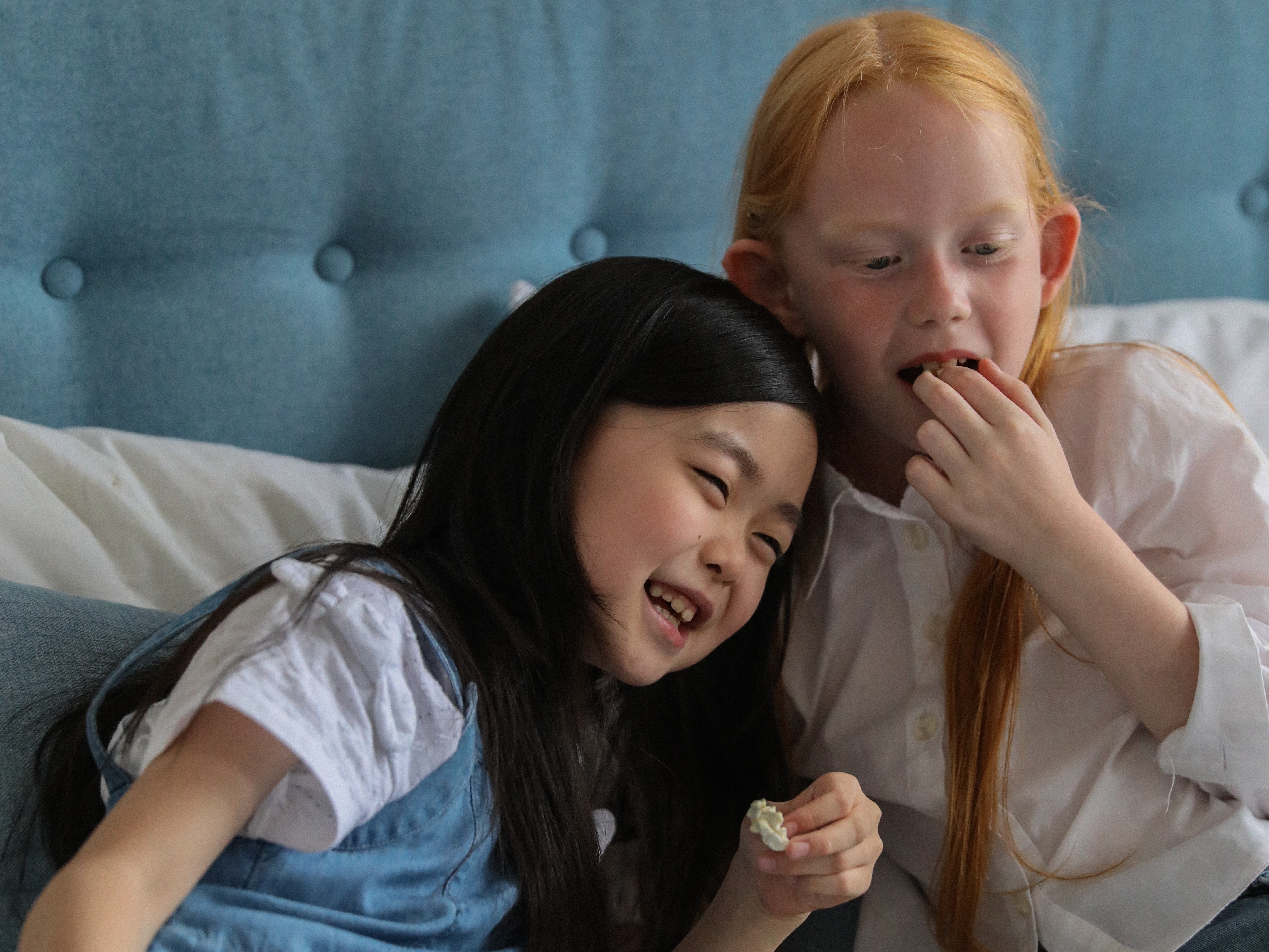 Friends eating popcorn on bed at home