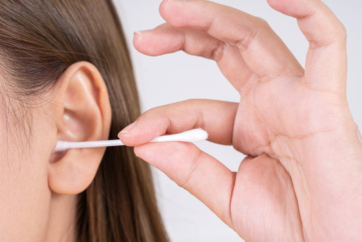Woman cleaning her ear with a cotton swab