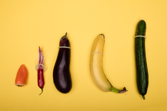 Line of vegetables with condoms on on yellow background