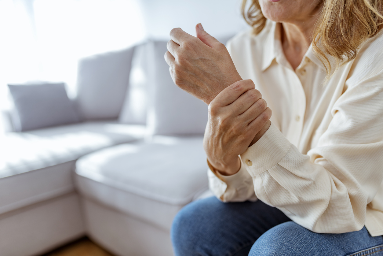 Woman holding her wrist while sitting on a sofa