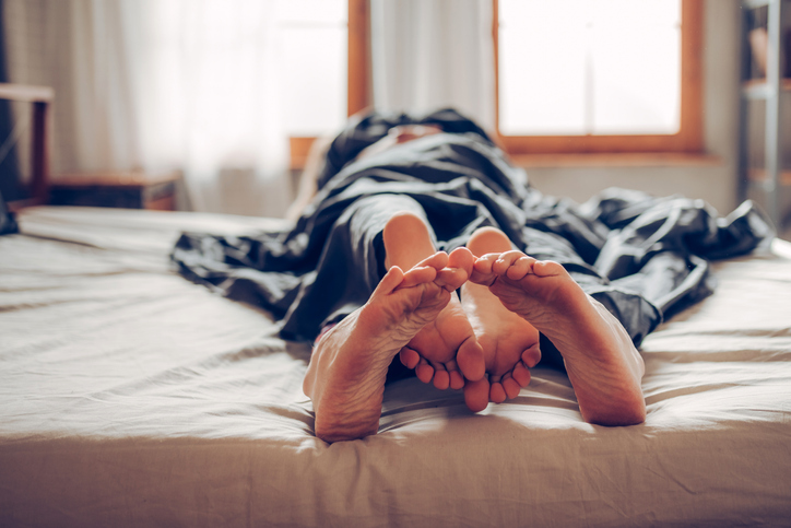 Young couple lying together in bed, close-up of feet