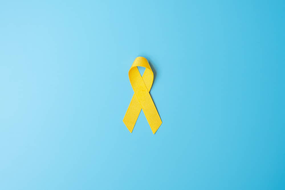 Yellow ribbon for sarcoma bone cancer awareness on blue background